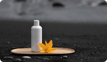 Minimalist product bottle displayed on a wooden tray with an orange flower on a dark background.
