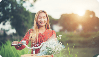 Smiling woman outdoors holding a basket filled with fresh flowers.