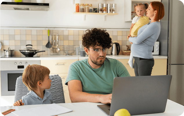 Parents multitasking between childcare and work responsibilities in home kitchen